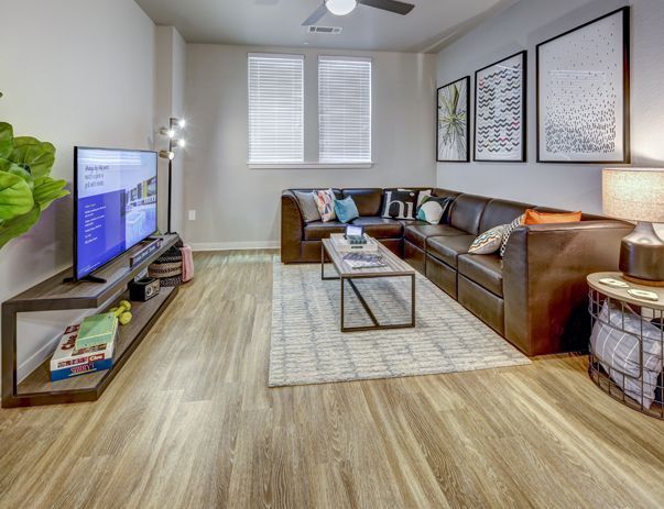A living room with a couch , coffee table , television and a ceiling fan.