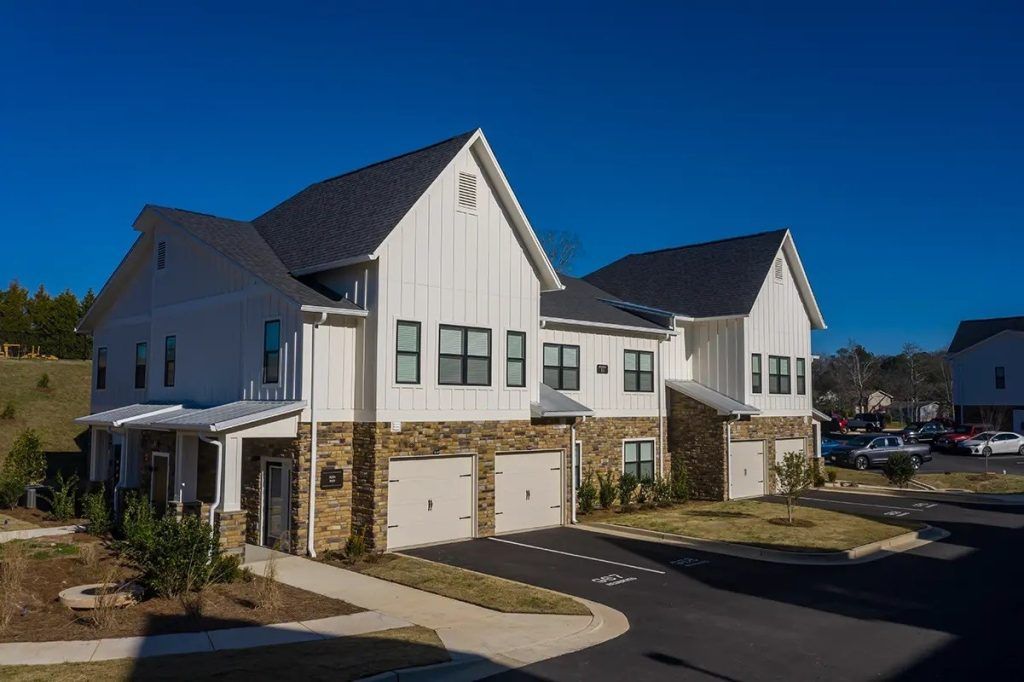 A row of white houses with black roofs are sitting next to each other in a residential area.