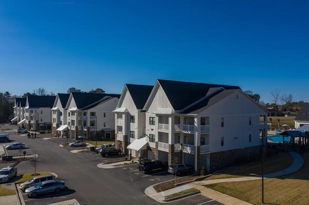 An aerial view of a row of apartment buildings with cars parked in front of them.