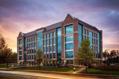 A large brick building with a lot of windows and a sunset in the background.