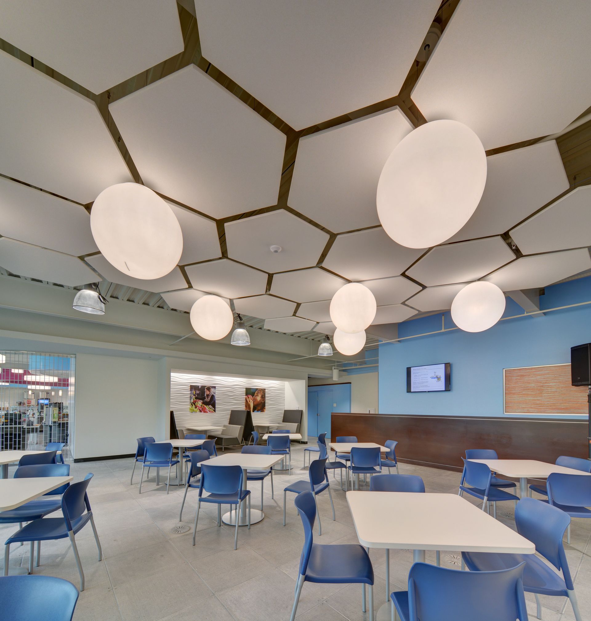 A large room with tables and chairs and a ceiling that looks like a honeycomb