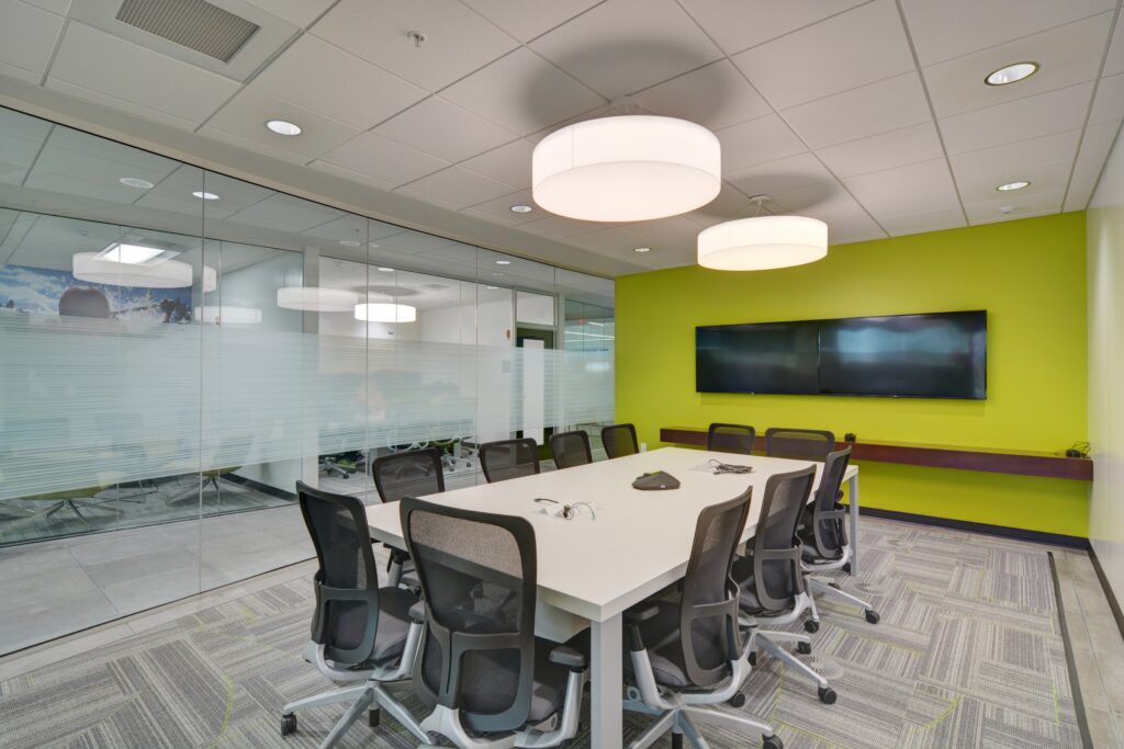 A conference room with a long table and chairs and a green wall.