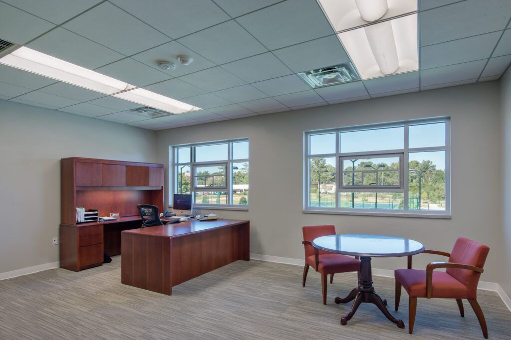 A large office with a desk , chairs and a table.