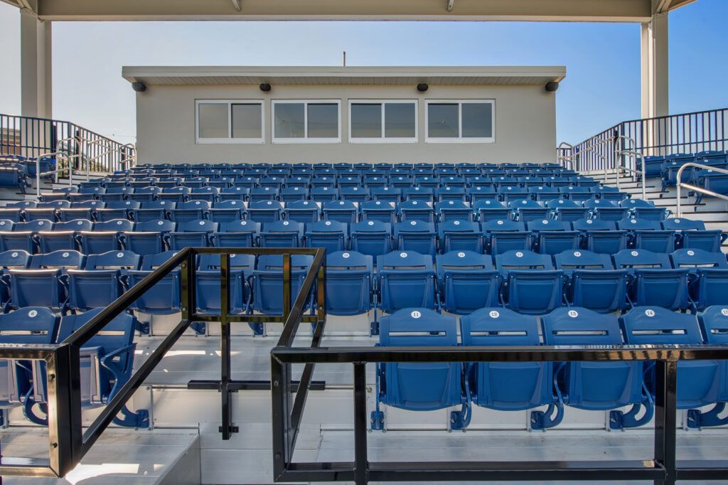 A stadium with rows of blue seats and a building in the background.