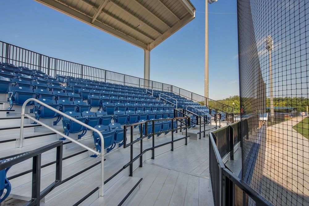 A baseball stadium with blue seats and a fence.
