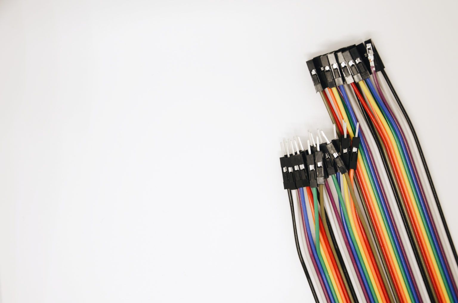 A bunch of rainbow colored wires sitting on top of each other on a white surface.