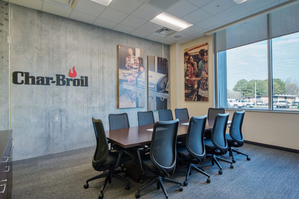 A conference room with a long table and chairs and a sign that says char-broil on the wall.