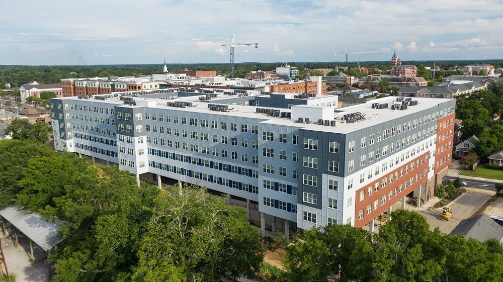 An aerial view of a large building surrounded by trees in a city.