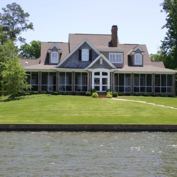 A large house sits on the shore of a lake