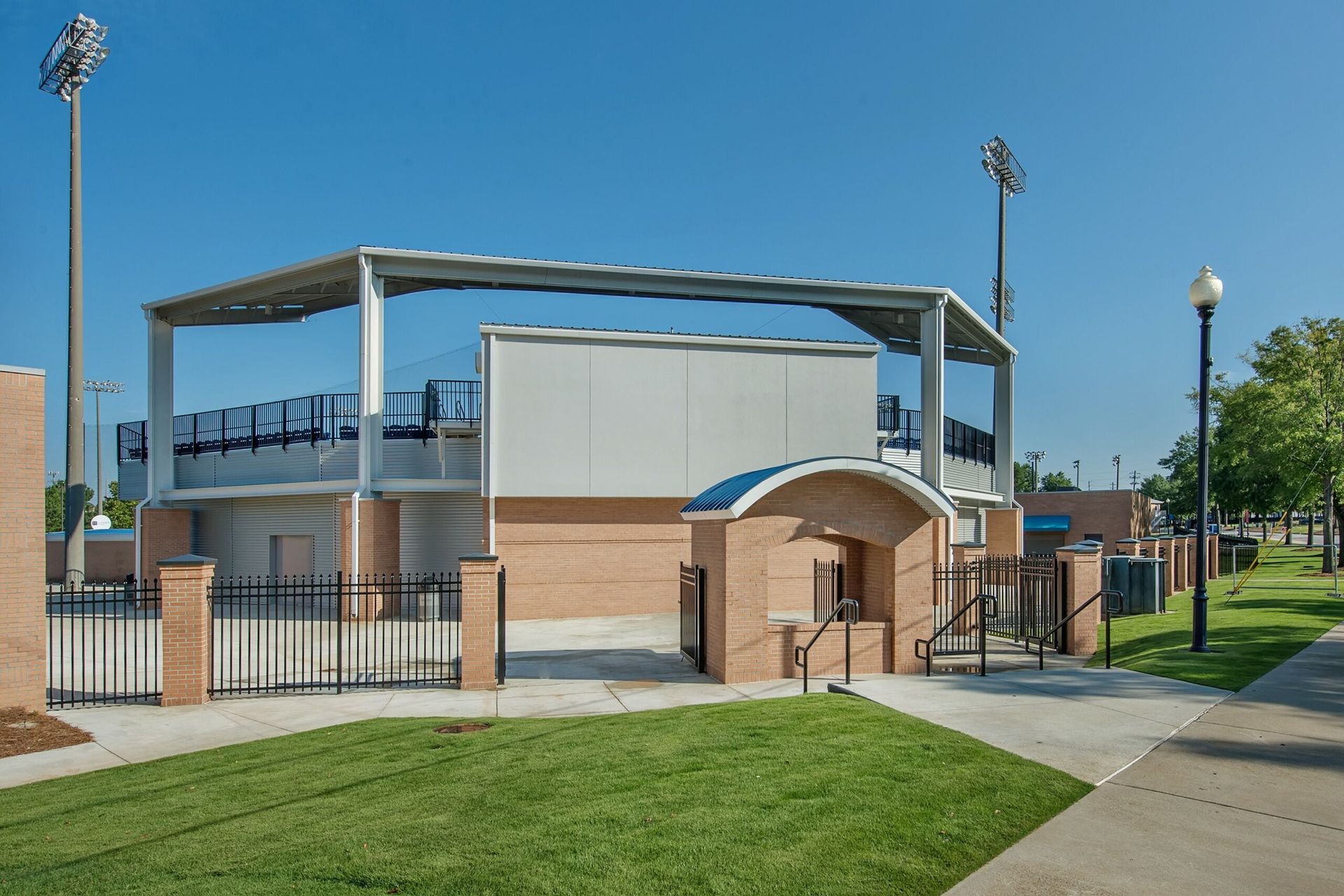 A large white building with a roof is surrounded by grass and a fence.