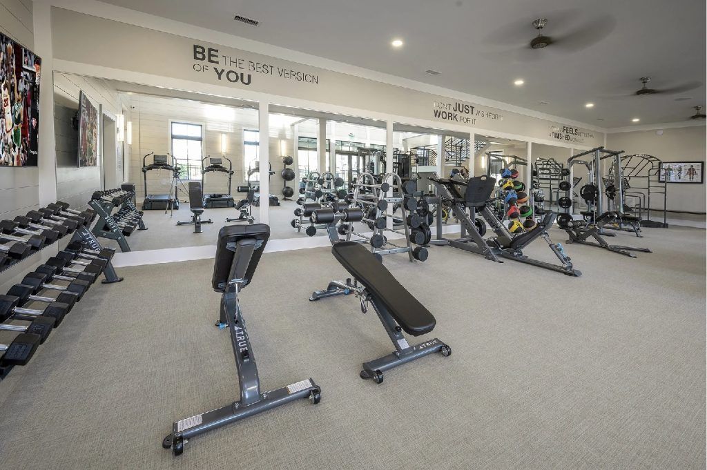A large gym filled with lots of exercise equipment and a bench.