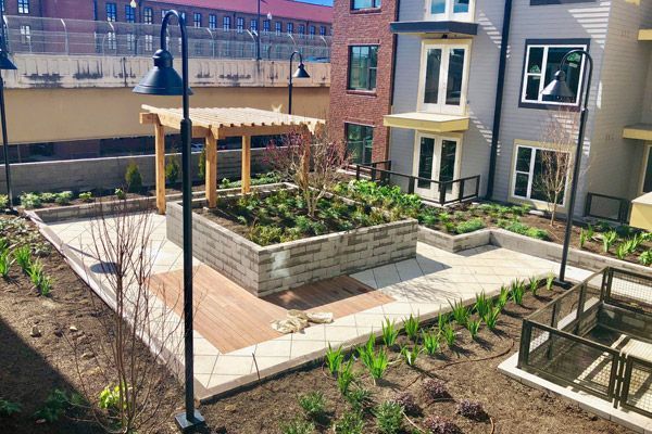 A courtyard with a pergola and planters in front of a building.