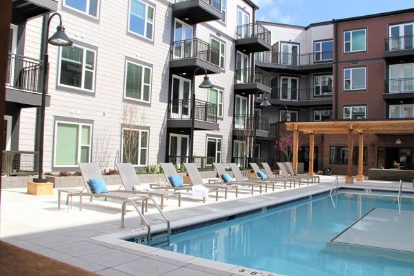 A large swimming pool surrounded by chairs in front of a building.