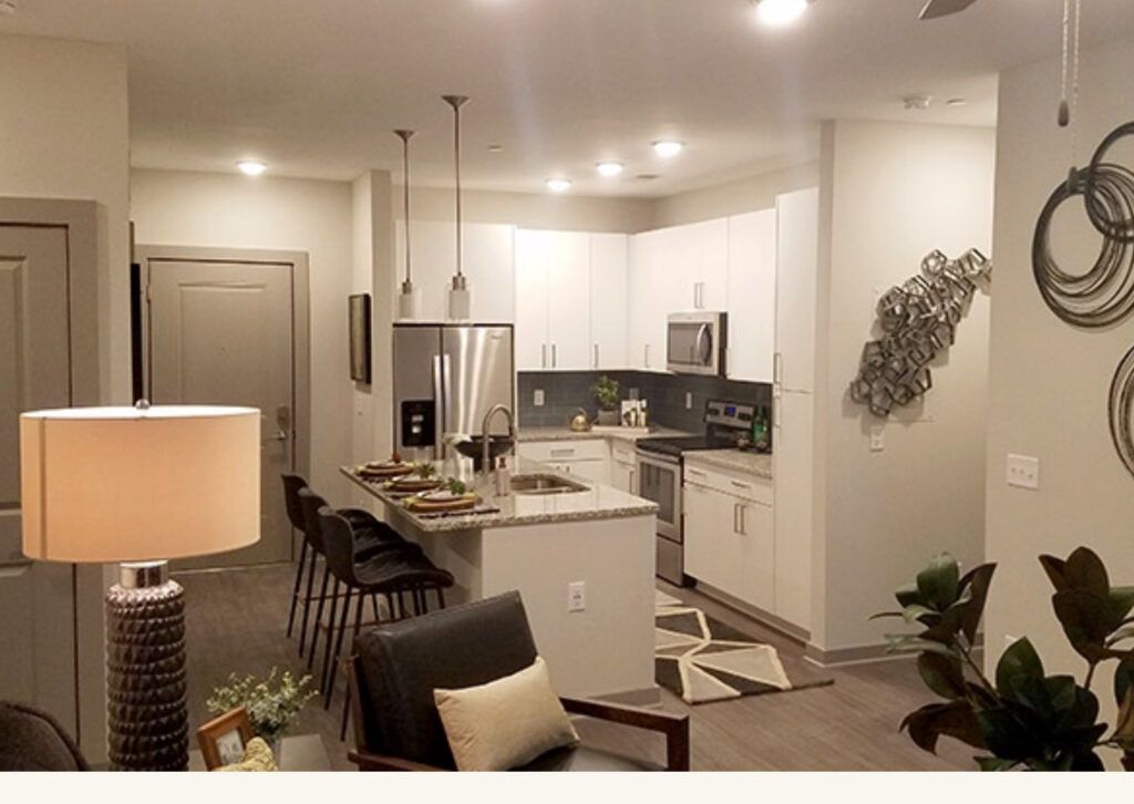 A living room with a large island in the middle of it and a kitchen.