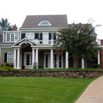 A large house with a stone wall in front of it