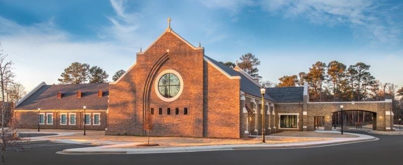 A large brick church with a clock on the front of it.