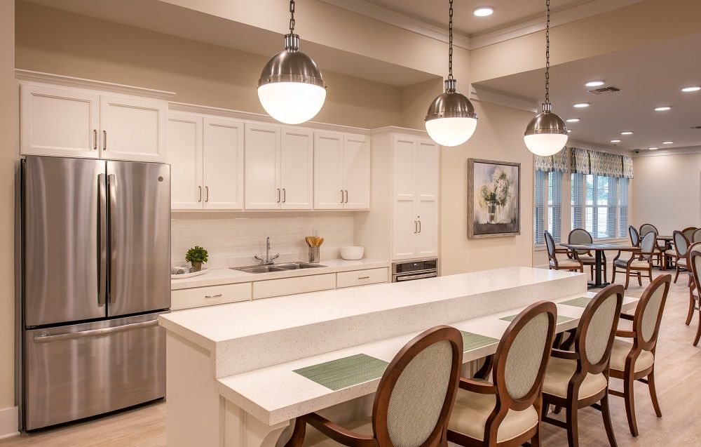 A kitchen with a long table and chairs and a refrigerator.