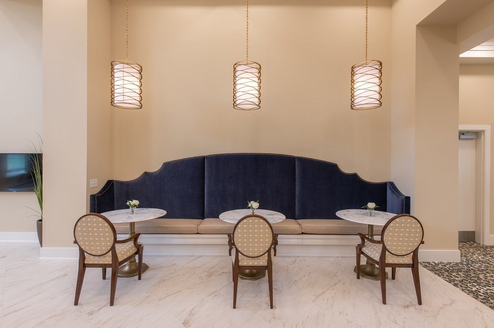 A lobby with tables and chairs and a blue couch.