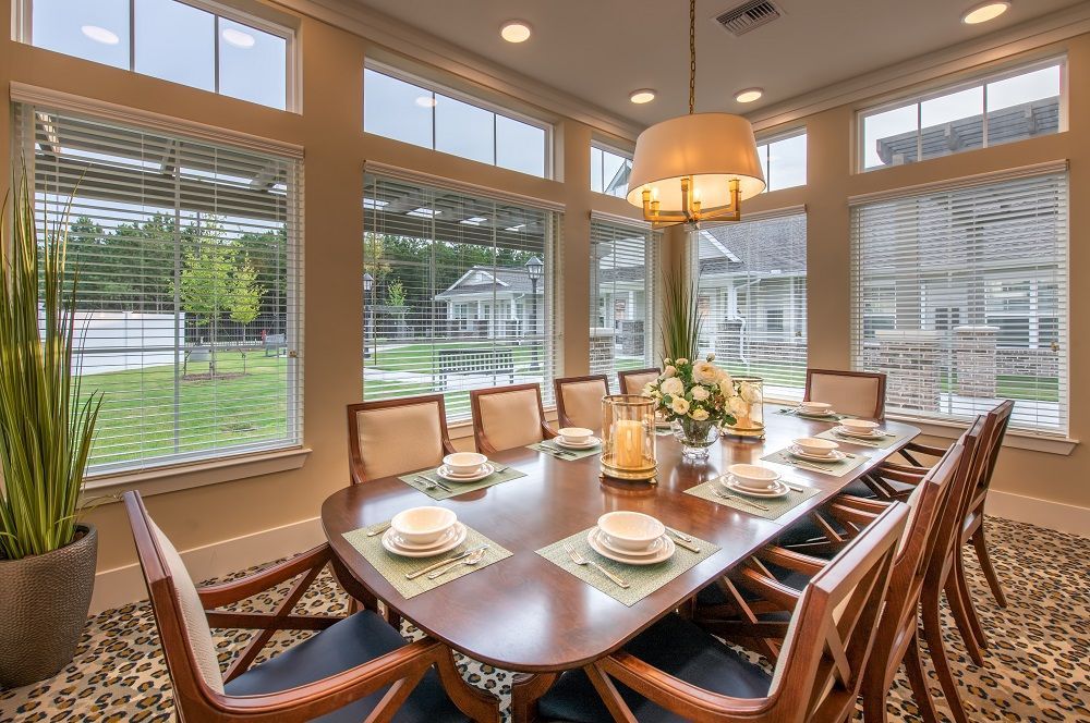 A dining room with a long table and chairs and a lot of windows.