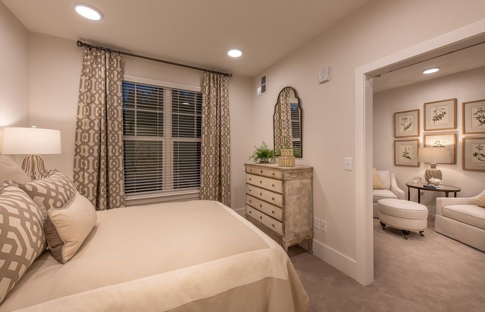 A bedroom with a bed , dresser , mirror and chairs.