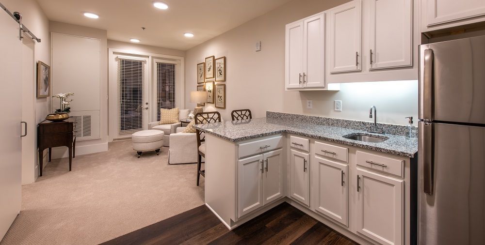A kitchen with white cabinets , granite counter tops , a refrigerator and a sink.