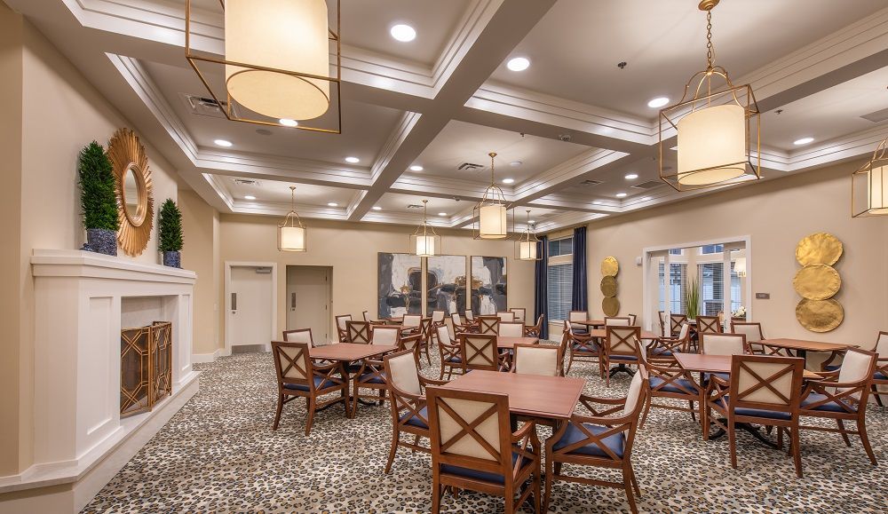 A large dining room with tables and chairs and a fireplace.
