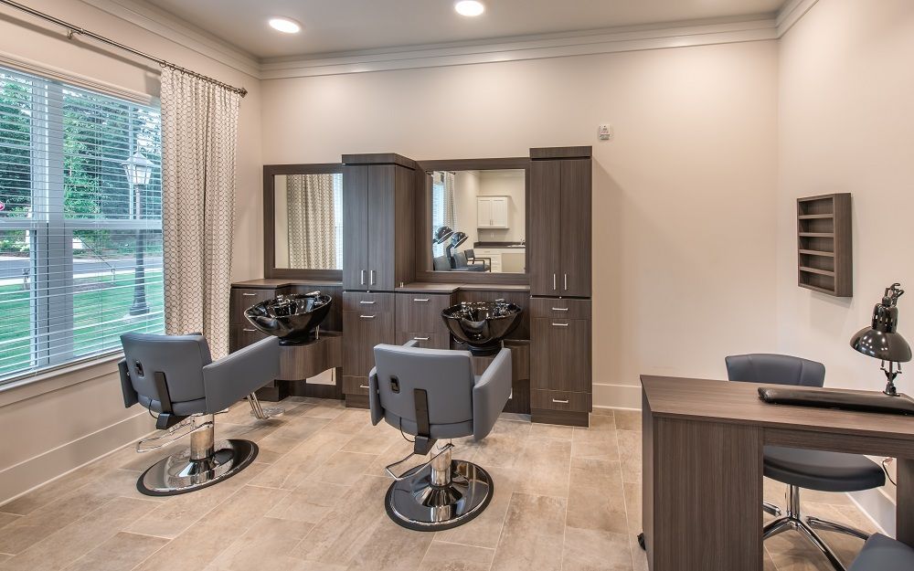 A salon with two chairs , a sink , a mirror and a table.