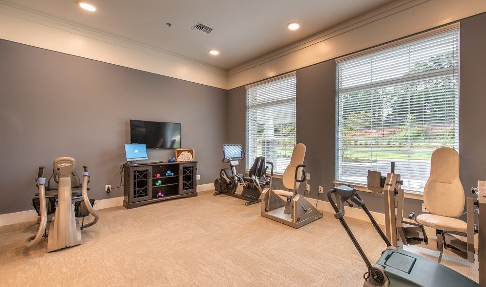 A gym with a lot of exercise equipment and a television.