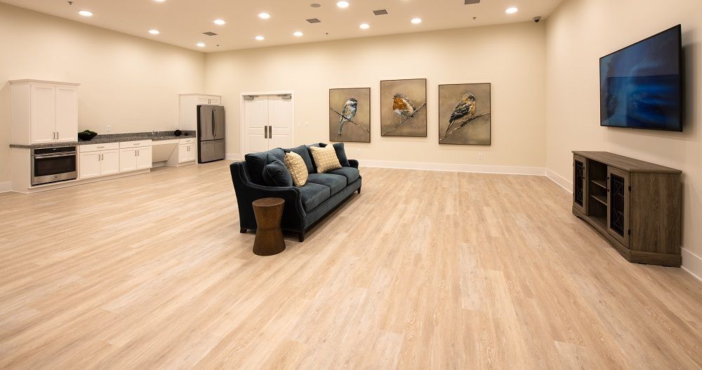 A living room with a couch , television , and paintings on the wall.