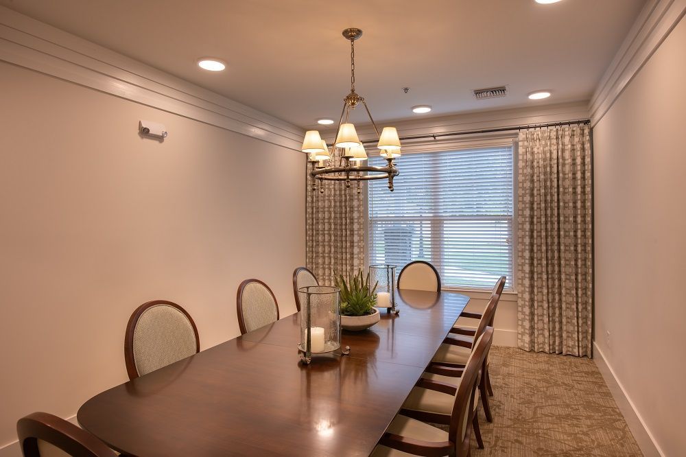 A dining room with a long table and chairs and a chandelier.