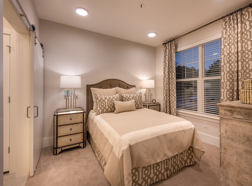 A bedroom with a large bed , two nightstands , a dresser and a window.