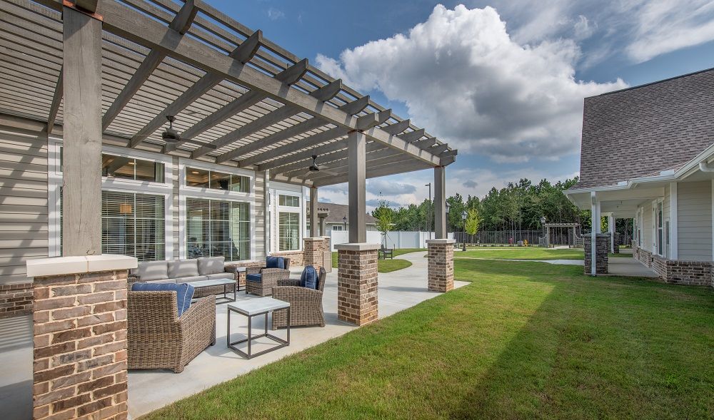 A patio area with a pergola and chairs in front of a house.