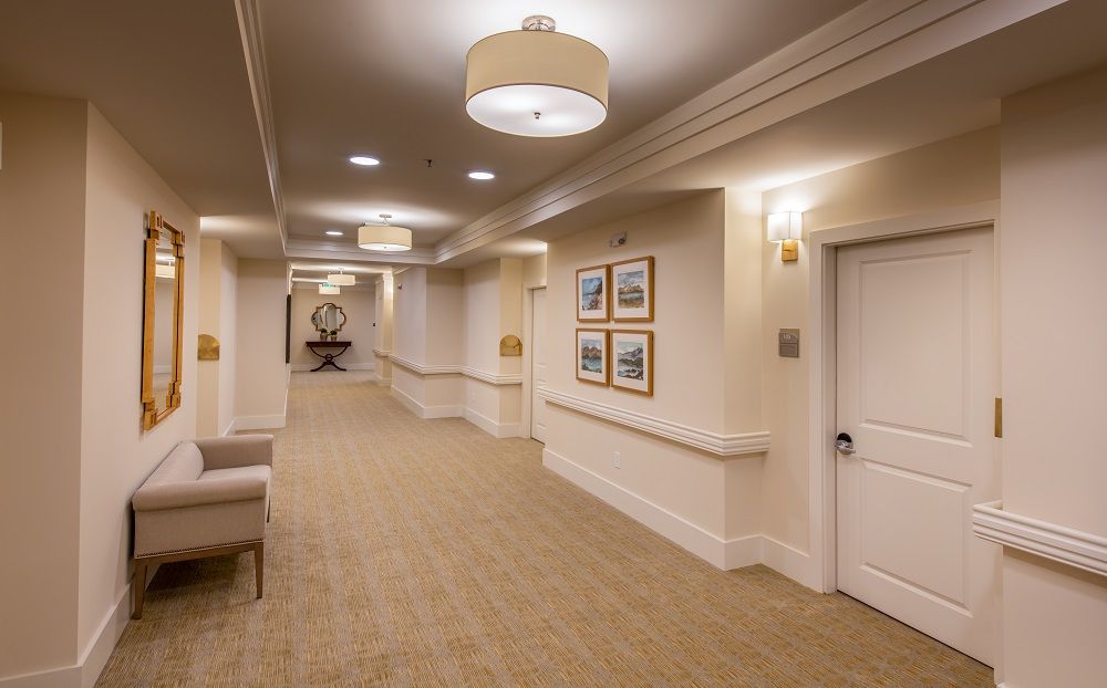A long hallway with a chair and a mirror on the wall.