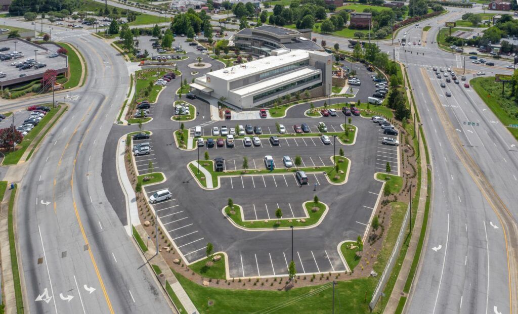 An aerial view of a parking lot surrounded by a highway and a building.