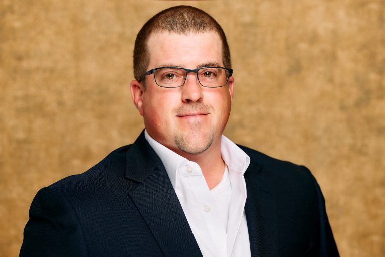 A man wearing glasses and a suit is posing for a picture.