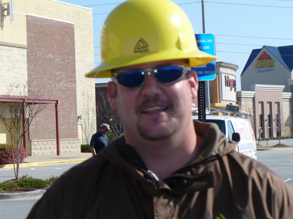 A man wearing a yellow hard hat and sunglasses
