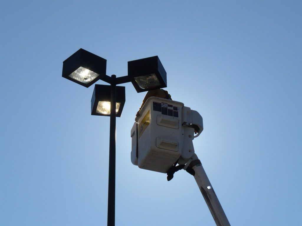 A person in a bucket is working on a street light