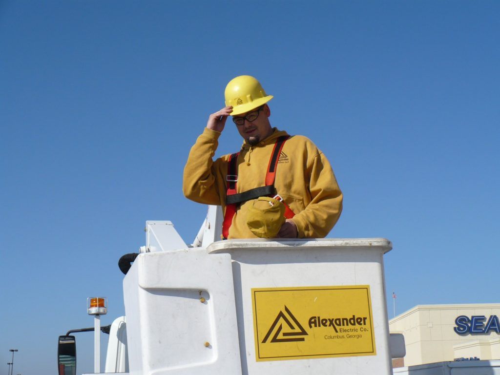 A man wearing a hard hat is standing in a alexander bucket