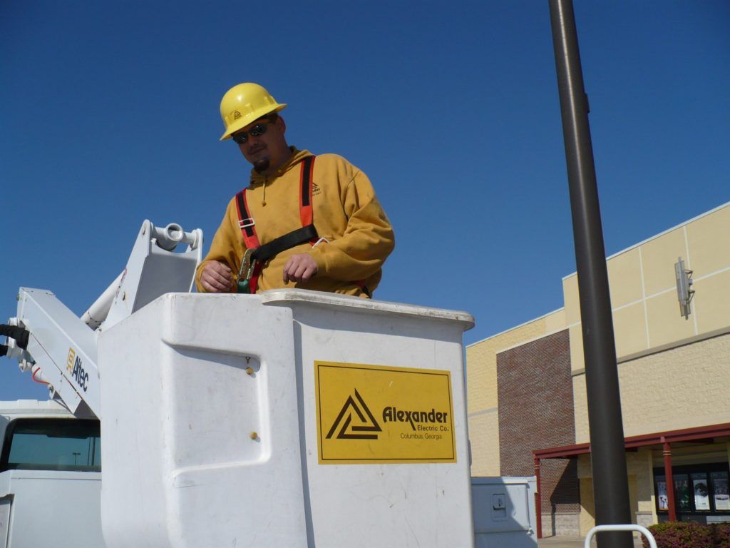 A man wearing a hard hat is working on a street light