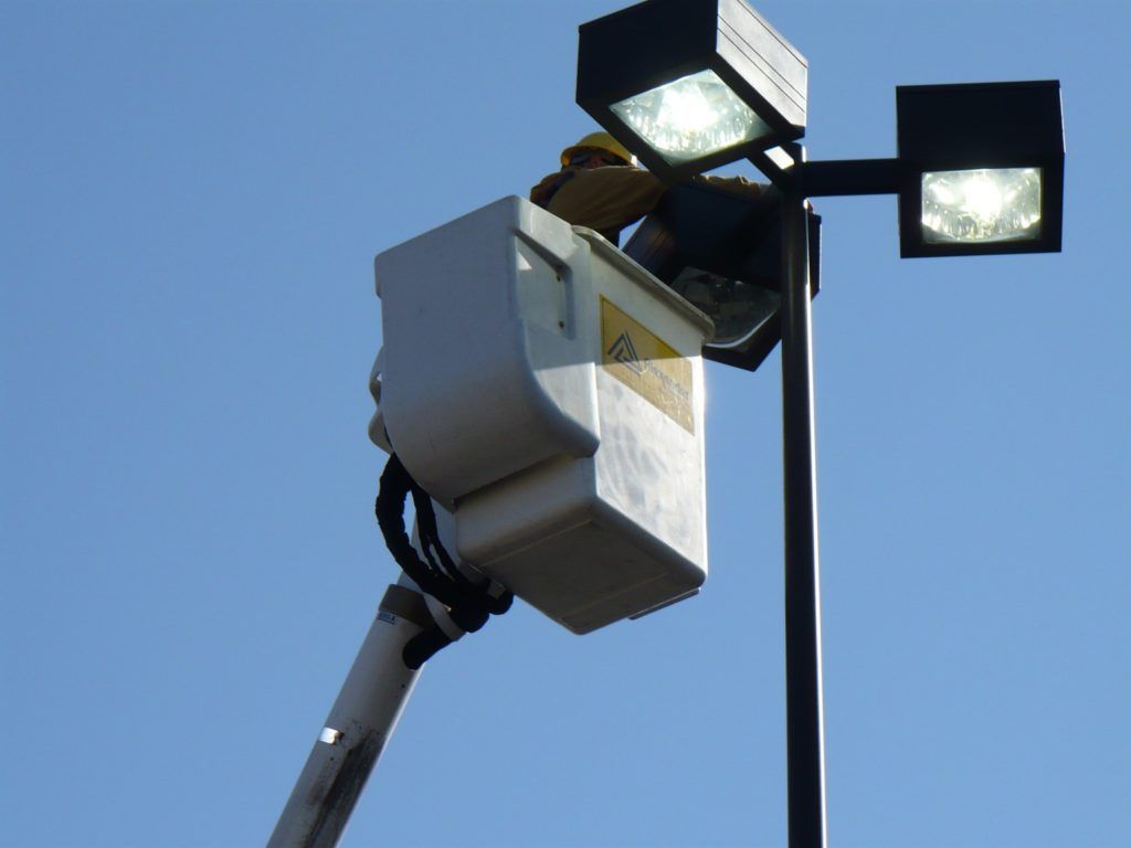 A man in a bucket is working on a street light