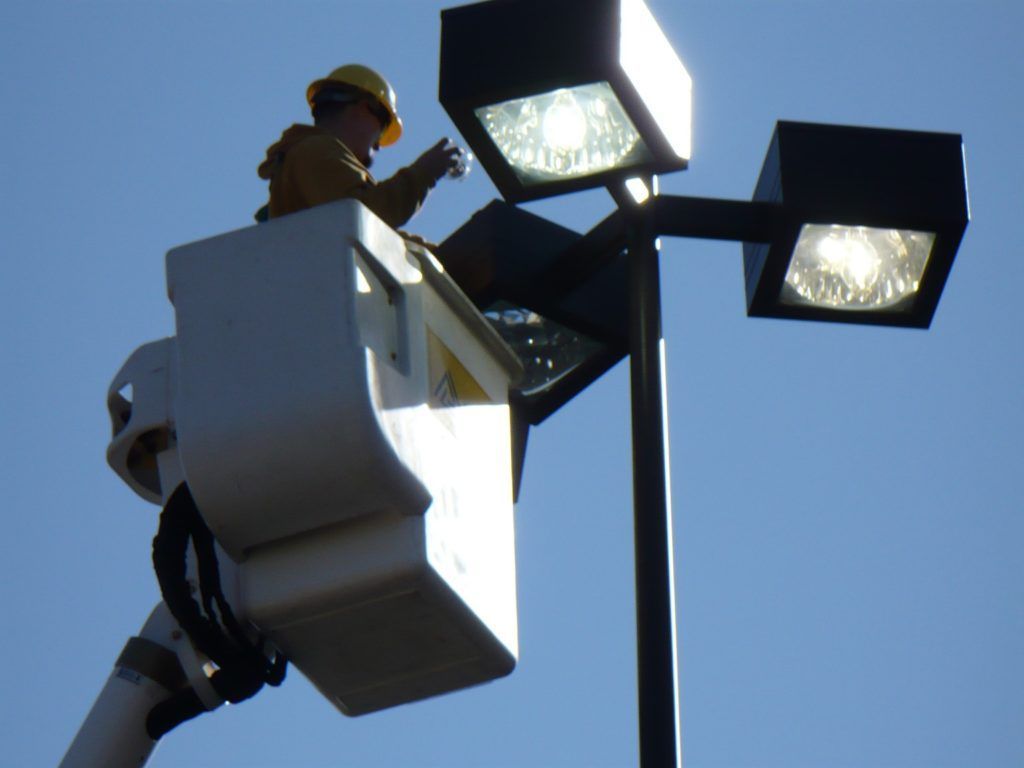 A man in a bucket is working on a street light