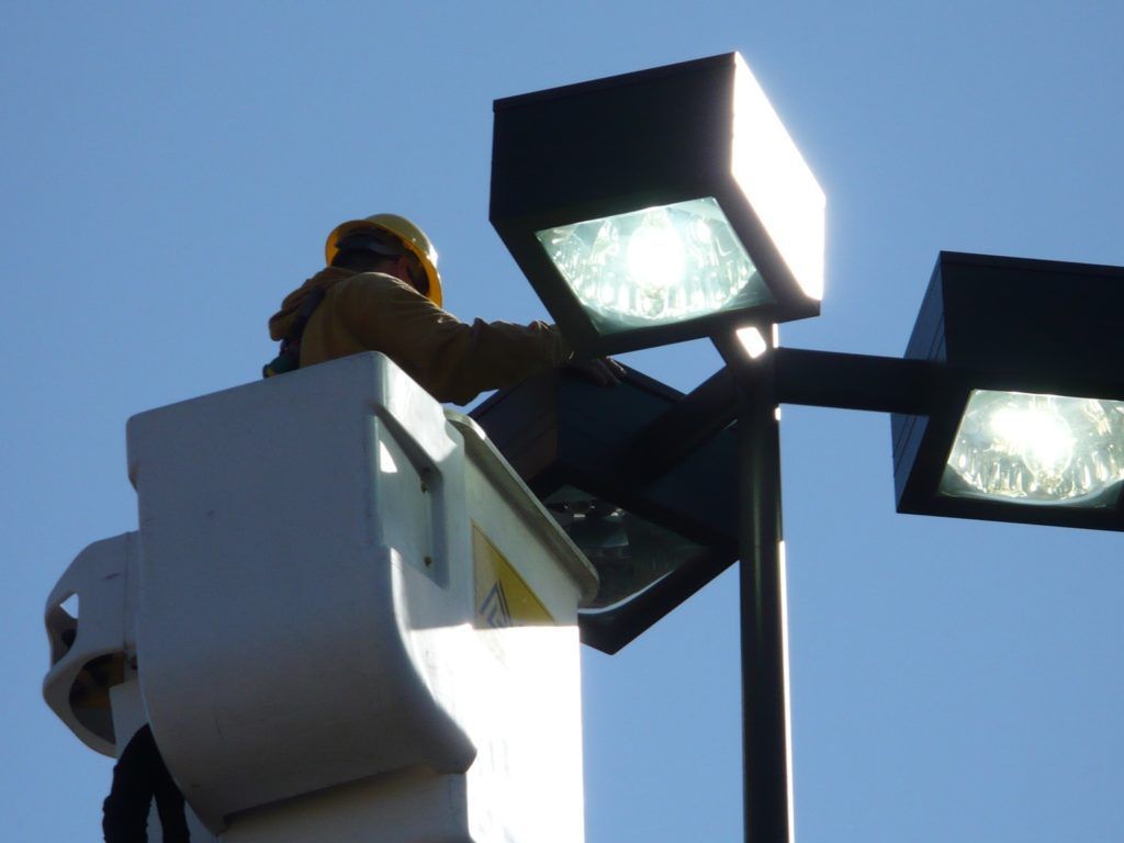A man in a bucket is working on a street light