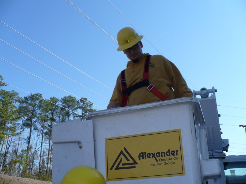 A man wearing a hard hat is standing in a alexander bucket