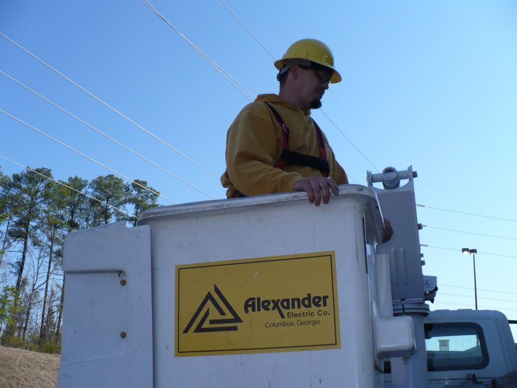 A man in a yellow hard hat is working on a alexander truck