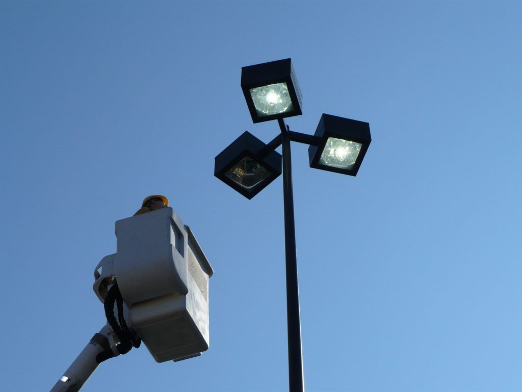 A man in a bucket is working on a street light