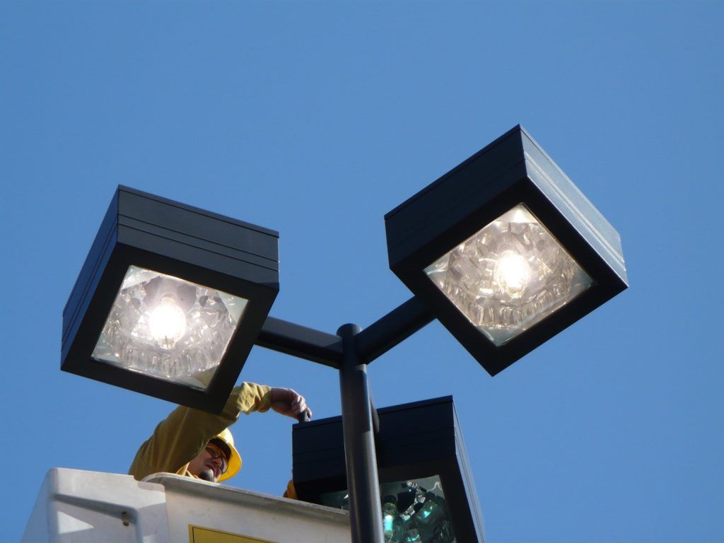 A man in a yellow raincoat is working on a street light