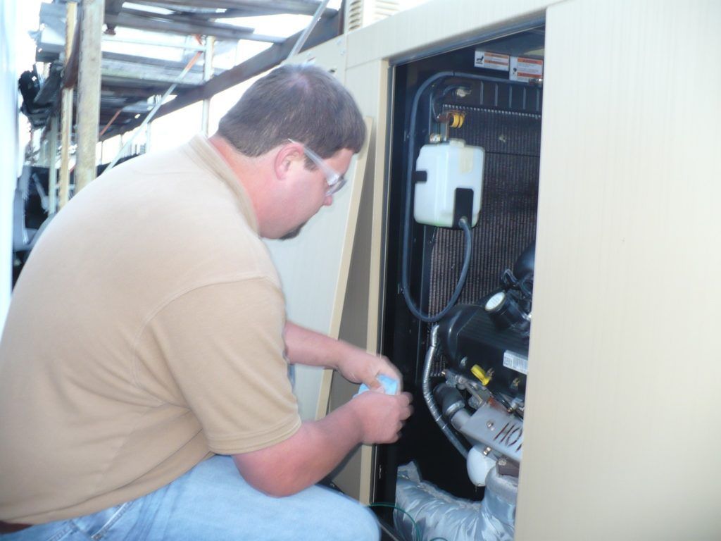 A man in a tan shirt is working on a machine