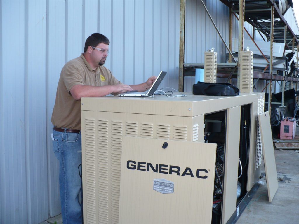 A man is working on a generator with a laptop