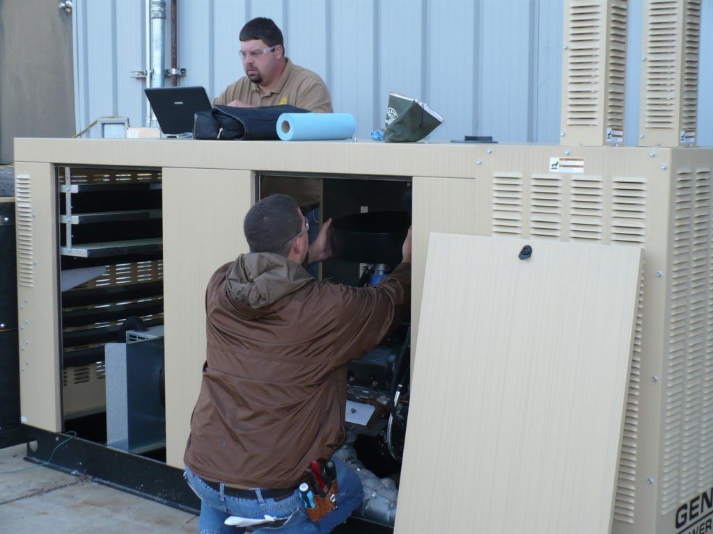Two men are working on a generator with the word gen on it