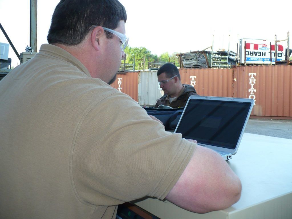 A man sitting at a desk with a laptop and a sign that says freight